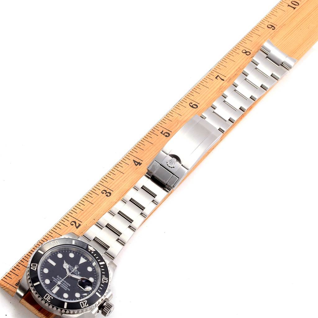 The image shows the Rolex Submariner 116610 Men's Stainless Steel Black Dial 116610 Men's Stainless Steel Black Dial watch laid flat against a ruler, displaying its face, bracelet, and clasp.