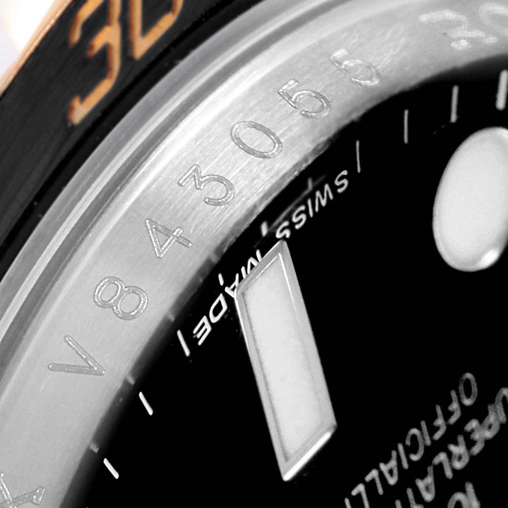 This close-up image of the Rolex Submariner 116613 Men's Steel and Gold (two tone) Black Dial 116613 Men's Steel and Gold (two tone) Black Dial model shows part of the bezel, serial number, and dial with a partial marker.