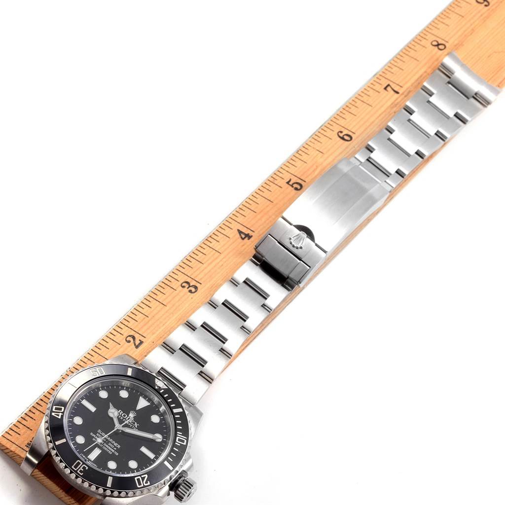 The image shows a Rolex Submariner 114060 Men's Stainless Steel Black Dial 114060 Men's Stainless Steel Black Dial watch laid flat with its bracelet extended alongside a wooden ruler for size reference.