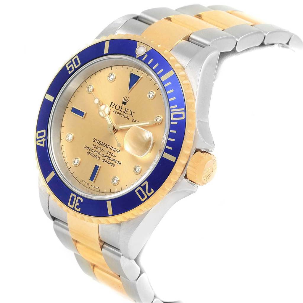 The Rolex Submariner 16613 Men's Steel and Gold (two tone) Champagne Dial 16613 Men's Steel and Gold (two tone) Champagne Dial watch shown here is angled from the front-left, highlighting the gold dial, blue bezel, and two-tone bracelet.