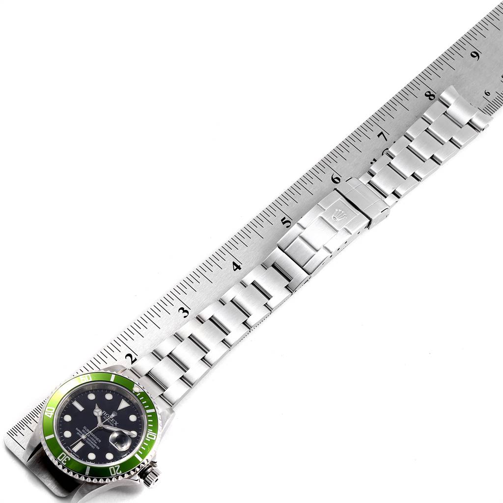The image shows a Rolex Submariner 16610LV Men's Stainless Steel Black Dial 16610LV Men's Stainless Steel Black Dial watch, focusing on its green bezel, black dial, and stainless steel bracelet next to a ruler.