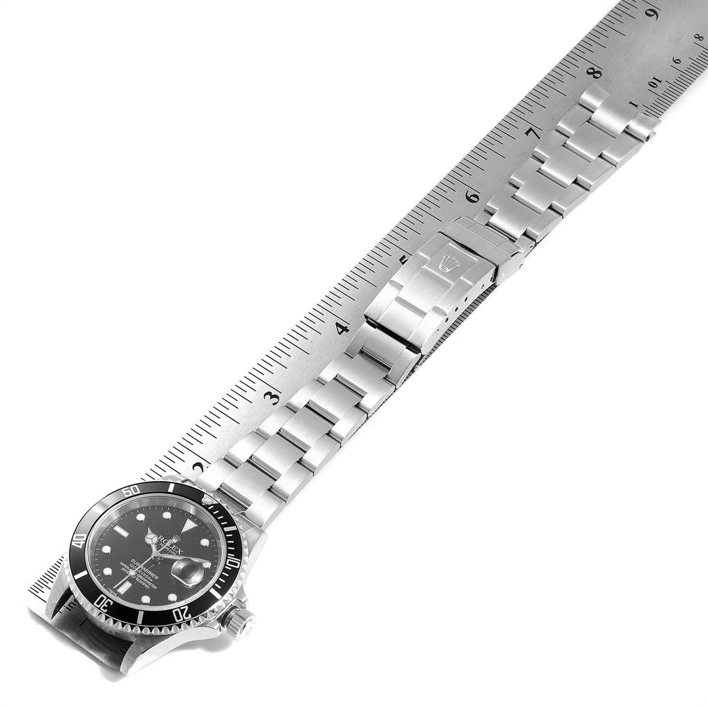 The image shows a Rolex Submariner 16610 Men's Stainless Steel Black Dial 16610 Men's Stainless Steel Black Dial watch laid flat, with its face and bracelet band displayed against a ruler.