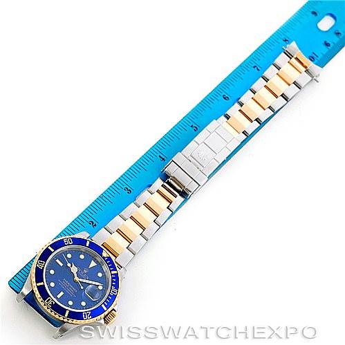 The image shows a Rolex Submariner 16613 Men's Steel and Gold (two tone) Blue Dial 16613 Men's Steel and Gold (two tone) Blue Dial watch laid flat, displaying the dial, bezel, and full length of the bracelet against a ruler.