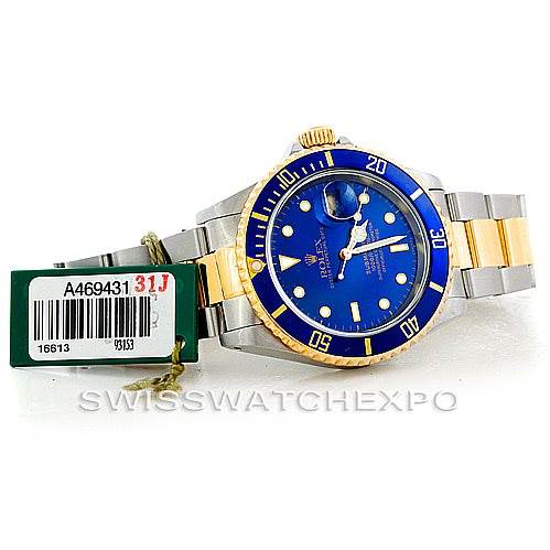 This image shows a Rolex Submariner 16613 Men's Steel and Gold (two tone) Blue Dial 16613 Men's Steel and Gold (two tone) Blue Dial watch with a blue dial, gold bezel, and two-tone bracelet from a front angle, along with its tags.