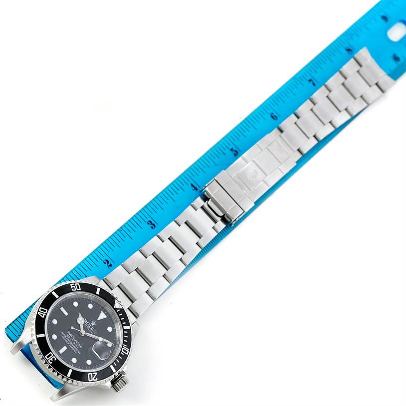 This top-down image shows the face and bracelet of a Rolex Submariner 16610 Men's Stainless Steel Black Dial 16610 Men's Stainless Steel Black Dial watch aligned with a ruler.