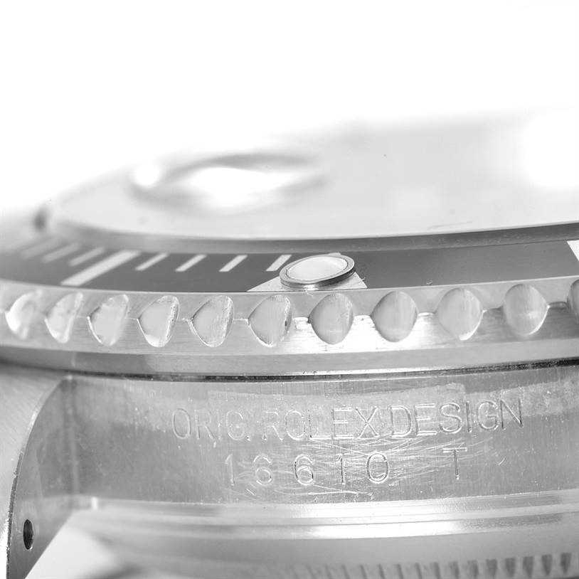 This close-up image of the Rolex Submariner 16610 Men's Stainless Steel Black Dial 16610 Men's Stainless Steel Black Dial watch showcases the bezel, indices, and engraved side of the case.