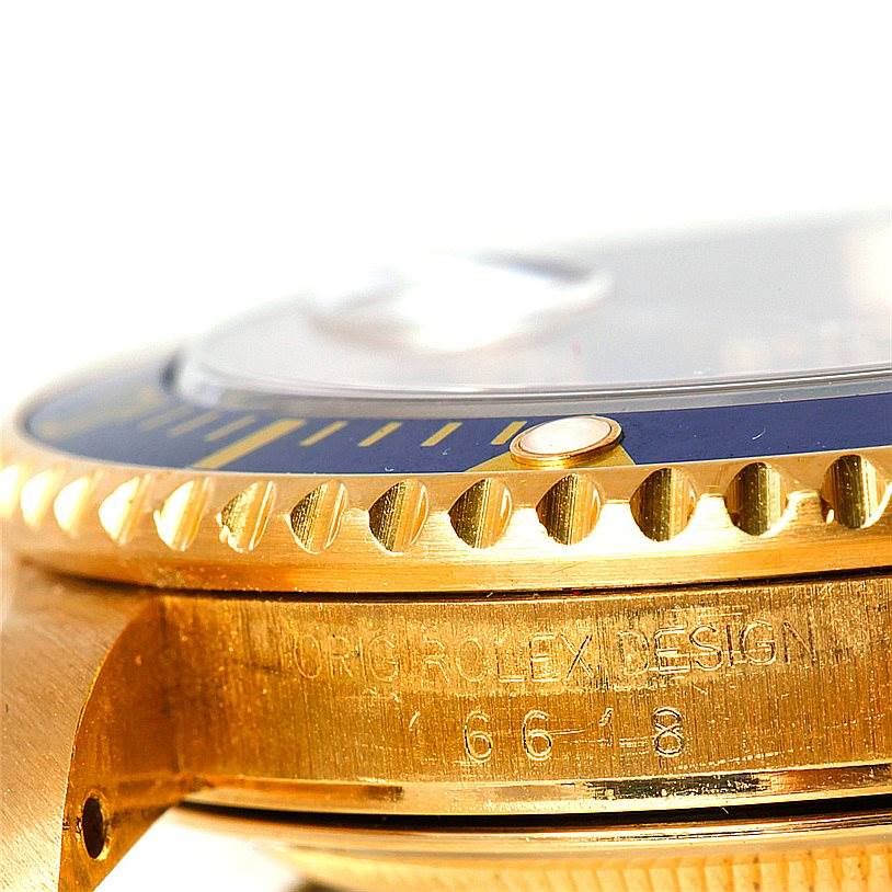 The image shows a close-up of the case side and bezel of a Rolex Submariner 16618 Men's Yellow Gold Blue Dial 16618 Men's Yellow Gold Blue Dial, emphasizing the engraving, crown guard, and bezel markings.
