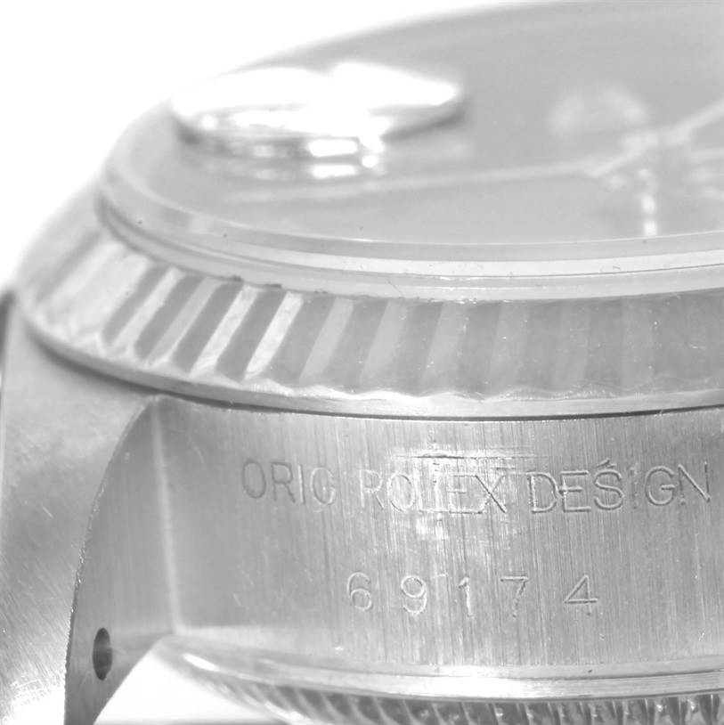 The image displays a close-up side view of a Rolex Datejust 69174 Women's Stainless Steel Black Dial 69174 Women's Stainless Steel Black Dial watch case, showing the model number and "ORIG ROLEX DESIGN" engraving.