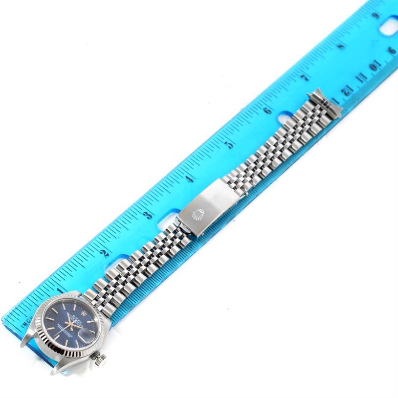 The image shows a top view of a Rolex Datejust 79174 Women's Stainless Steel Blue Dial 79174 Women's Stainless Steel Blue Dial watch with a jubilee bracelet alongside a blue ruler for scale.