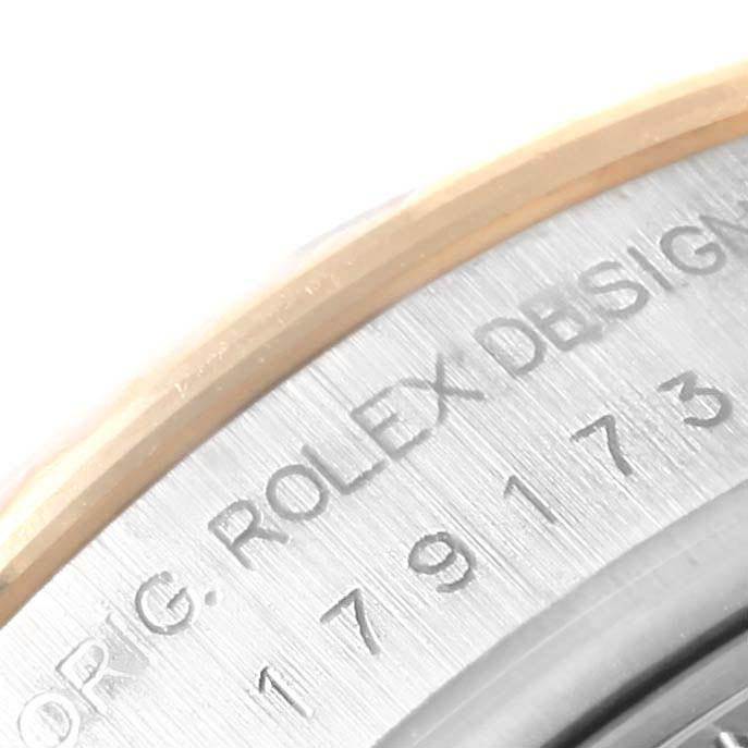 The image shows a close-up of the case side of a Rolex Datejust 179173 Women's Steel and Gold (two tone) Black Dial 179173 Women's Steel and Gold (two tone) Black Dial, featuring part of the engraved serial number and "ROLEX DESIGN."