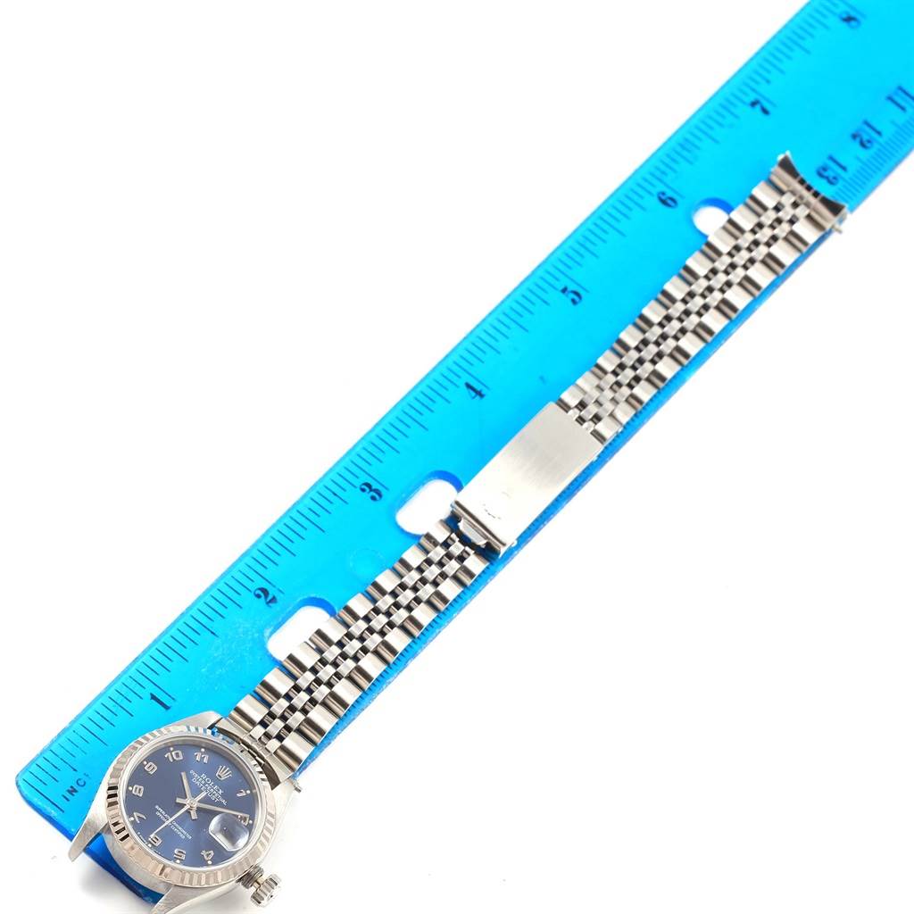 The image shows a Rolex Datejust 69174 Women's Stainless Steel Blue Dial 69174 Women's Stainless Steel Blue Dial watch, featuring the face and stainless steel and gold Jubilee bracelet, aligned with a blue ruler.