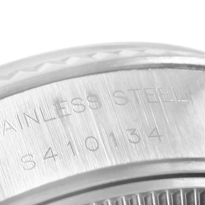 This image shows a close-up of the side of a Rolex Datejust 69174 Women's Stainless Steel Blue Dial 69174 Women's Stainless Steel Blue Dial watch, focusing on the engraved serial number and "STAINLESS STEEL".