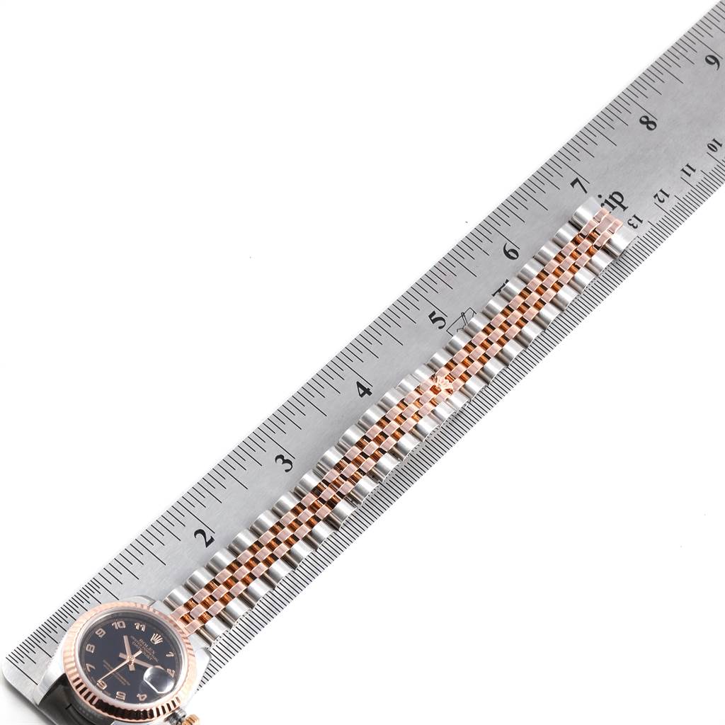 The image shows the top view of a Rolex Datejust 179171 Women's Steel and Gold (two tone) Black Dial 179171 Women's Steel and Gold (two tone) Black Dial watch, focusing on the face and part of the band, placed alongside a ruler.