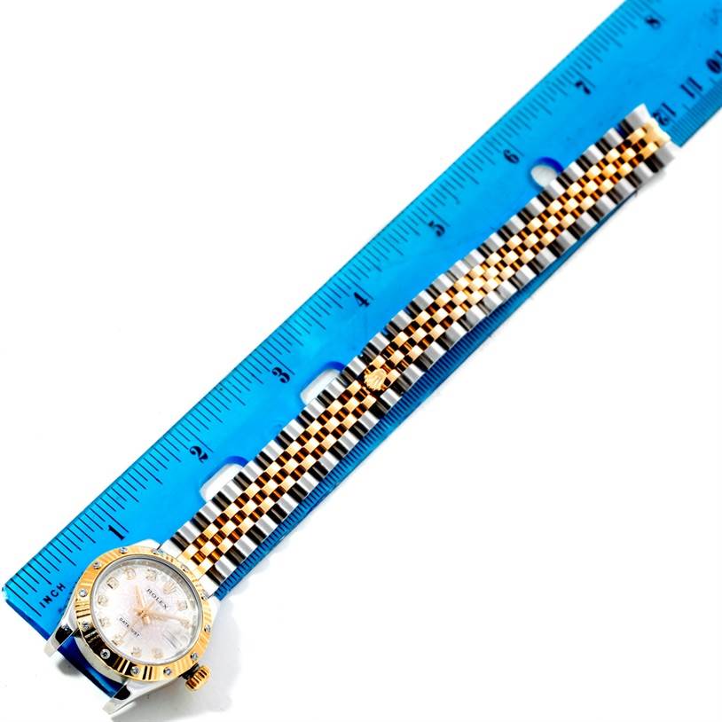 The Rolex Datejust 179313 Women's Stainless Steel Beige Dial 179313 Women's Stainless Steel Beige Dial watch is shown from a top-down angle, displaying its dial, bezel, and two-tone bracelet beside a blue ruler.