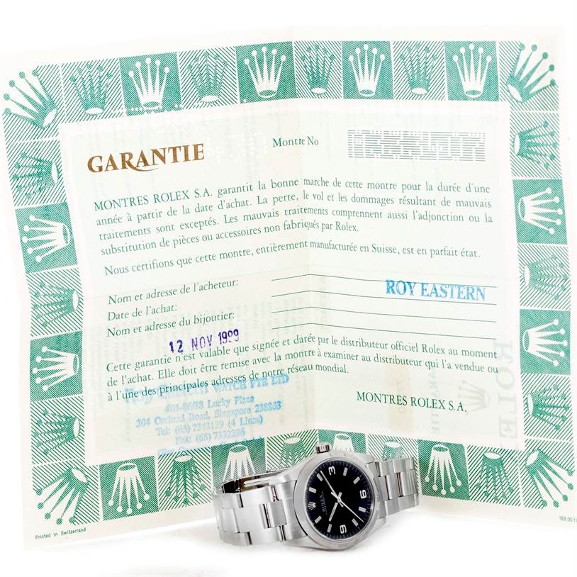 The image shows a Rolex Mid-Size 77080 Men's Stainless Steel Black Dial 77080 Men's Stainless Steel Black Dial model watch and a warranty certificate, viewed from the front.