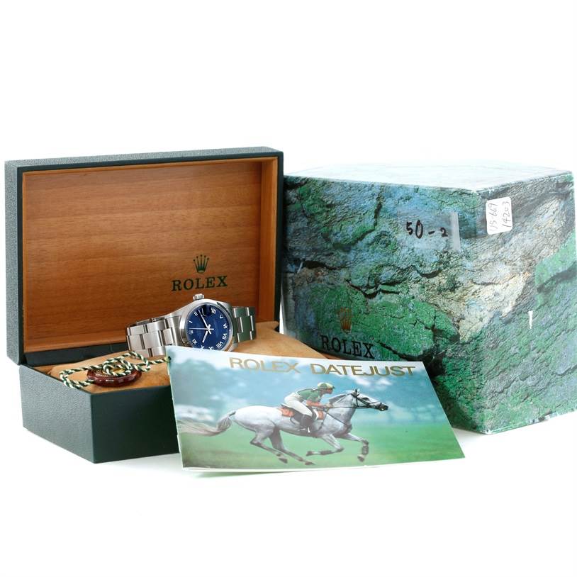 The image shows a Mid-Size Rolex Datejust watch in its open box with a booklet and outer packaging present.