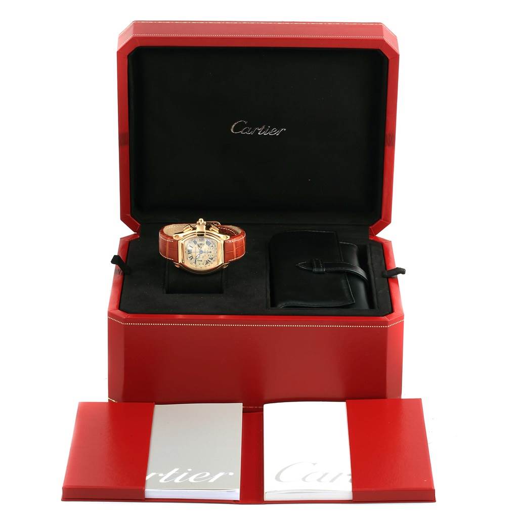 The Cartier Roadster W62021Y3 Men's Yellow Gold Champagne Dial W62021Y3 Men's Yellow Gold Champagne Dial watch is shown in its open red box, along with a booklet and additional accessory pouch.
