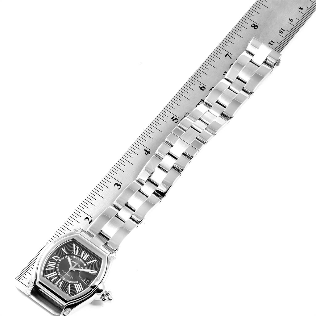 The image shows a Cartier Roadster W62041V3 Men's Stainless Steel Black Dial W62041V3 Men's Stainless Steel Black Dial watch laid flat beside a ruler, displaying its face and metal bracelet.