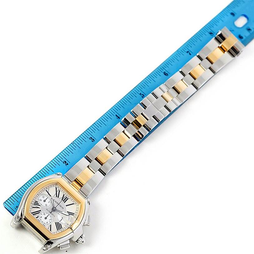 This image shows a Cartier Roadster W62027Z1 Men's Steel and Gold (two tone) Silver Dial W62027Z1 Men's Steel and Gold (two tone) Silver Dial watch and its metal bracelet laid next to a ruler at an overhead angle, highlighting its full length.