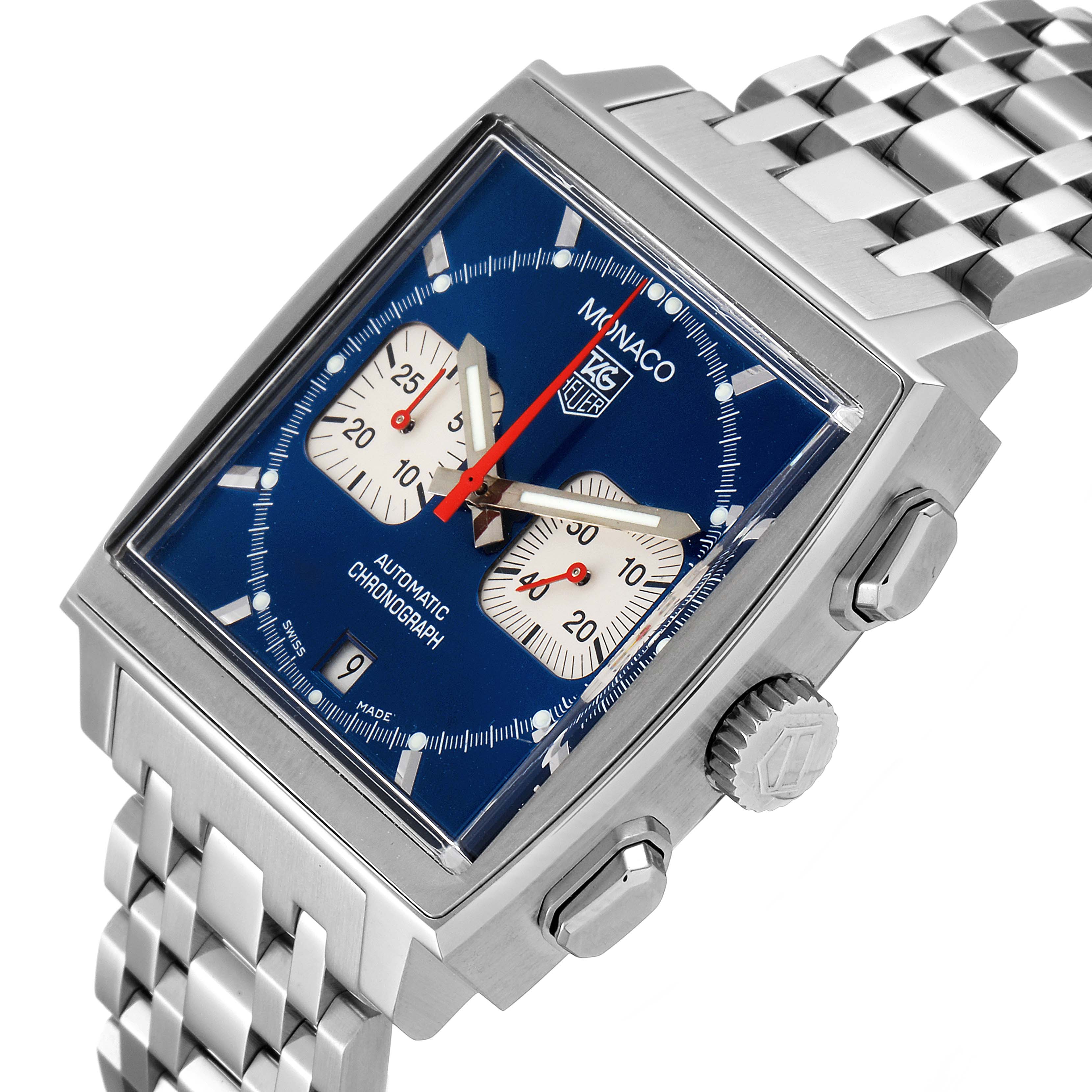 The image shows a close-up, angled view of the Monaco model watch by Tag Heuer, highlighting its blue dial, square case, and metal bracelet.
