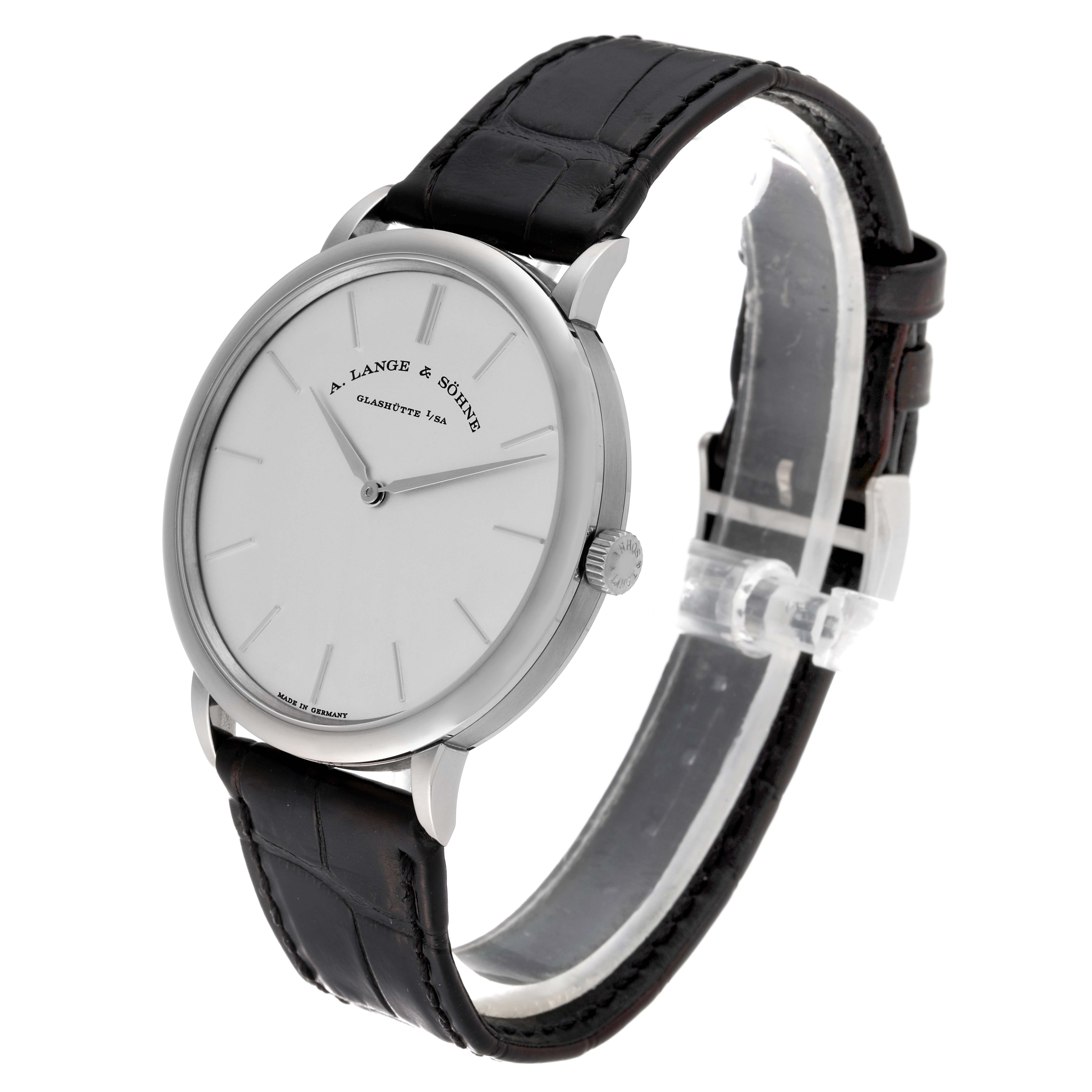 The image shows the A. Lange & Sohne Saxonia 211.027 Men's White Gold Silver Dial watch at a three-quarter angle, displaying its dial, bezel, and leather strap.