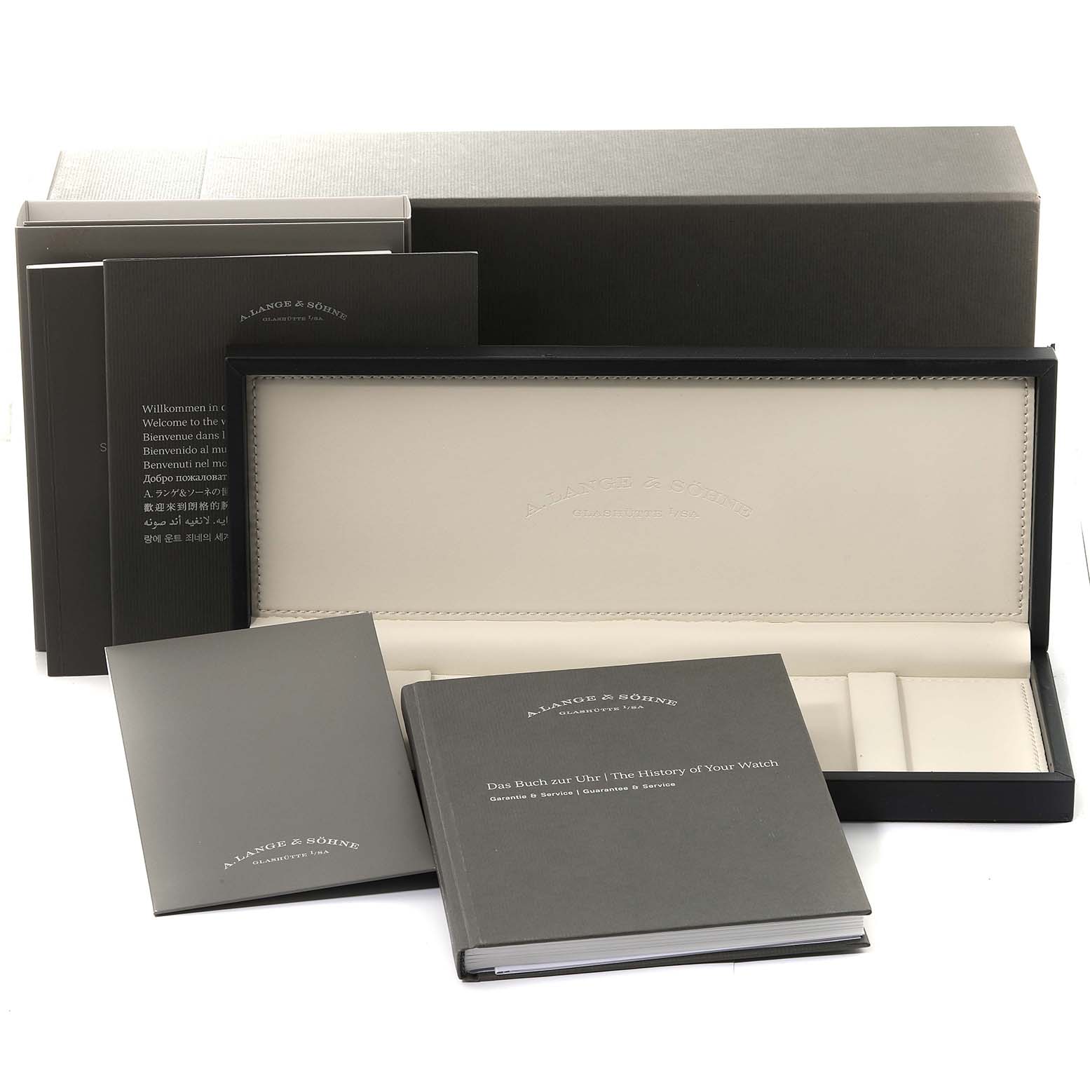 The image displays the packaging and accompanying booklets for the Saxonia watch by A. Lange & Söhne.