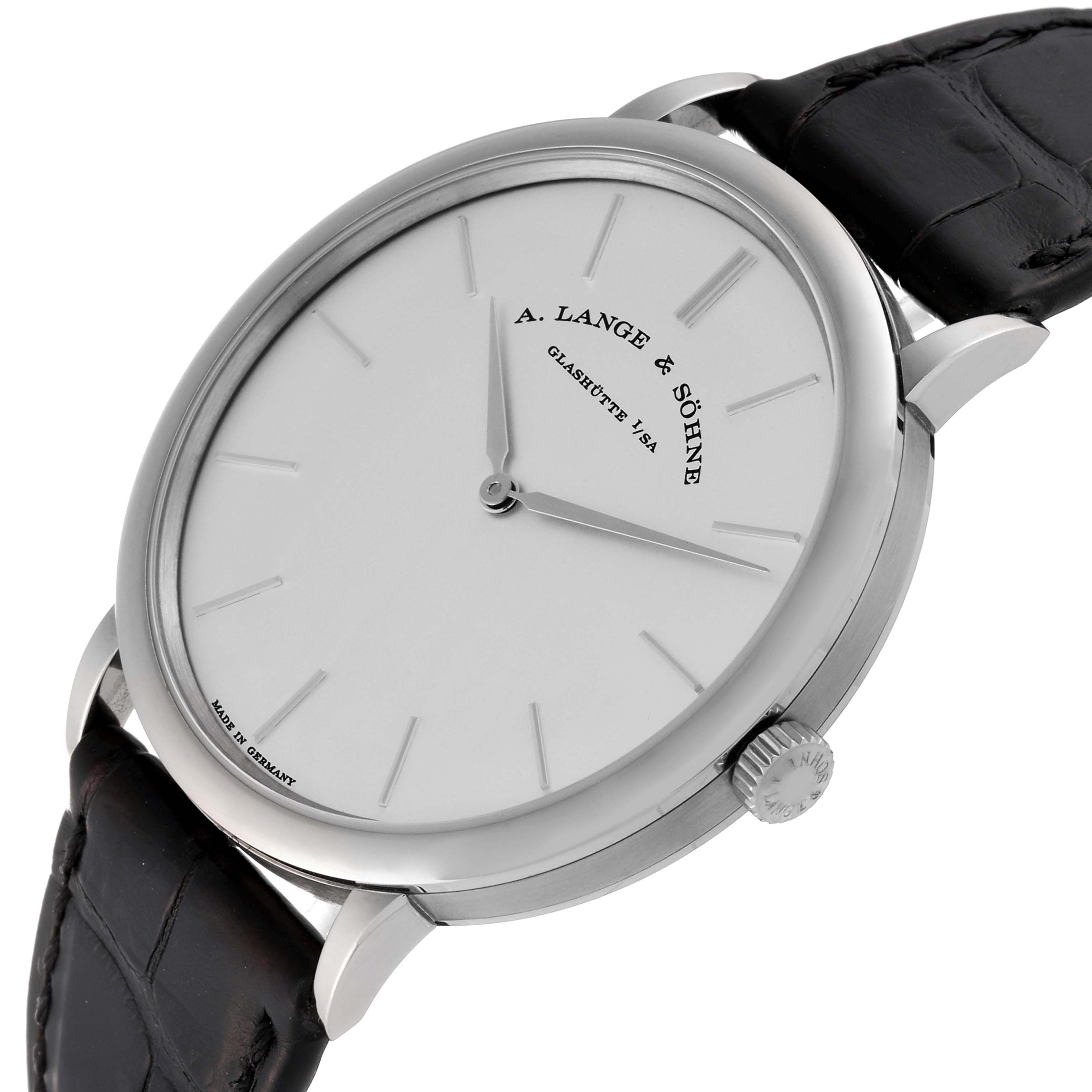 The image shows a close-up of the A. Lange & Sohne Saxonia 211.027 Men's White Gold Silver Dial watch at a slight angle, highlighting its face, crown, and leather strap.