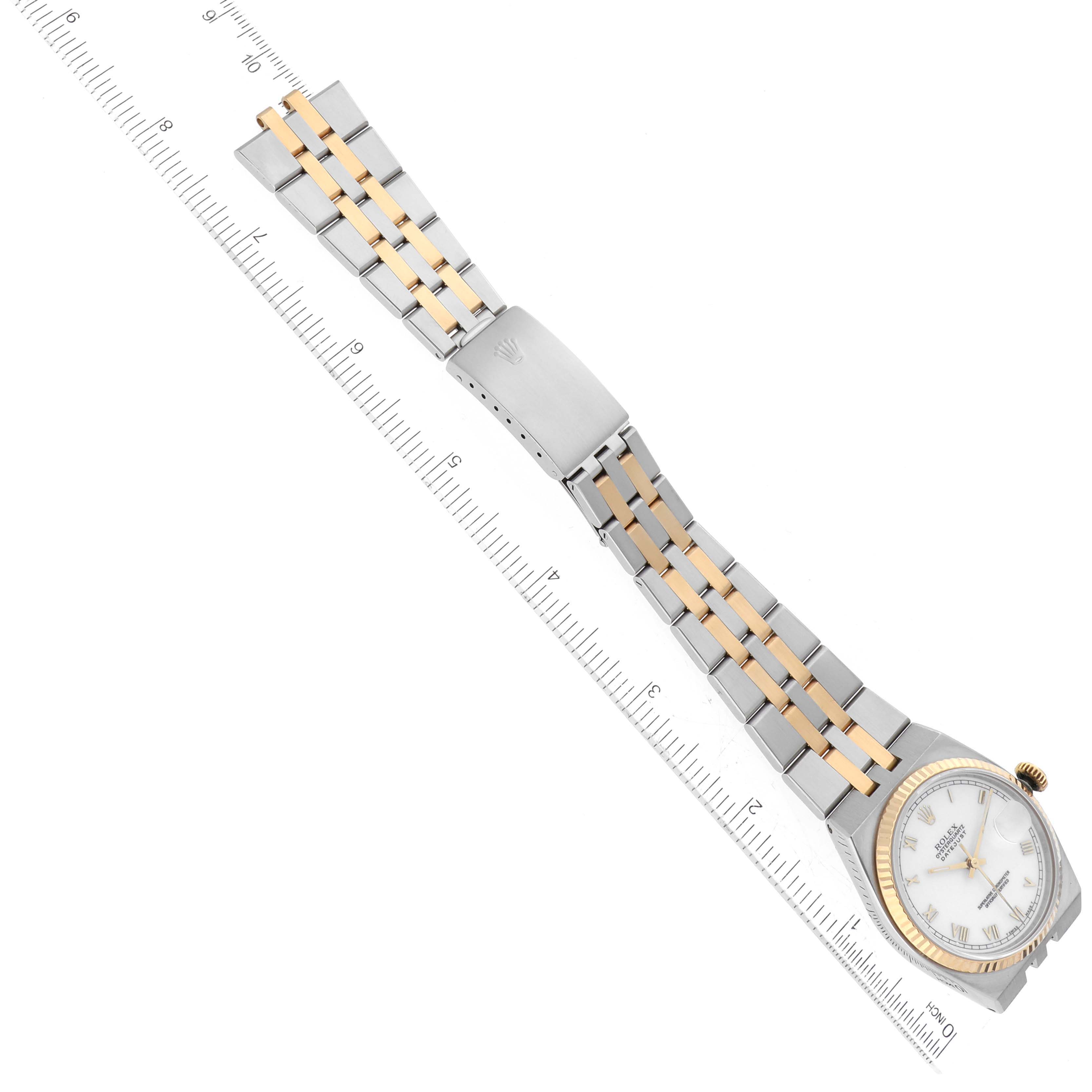 The image shows a top-down view of a Rolex Oysterquartz 17013 Men's Steel and Gold (two tone) White Dial 17013 Men's Steel and Gold (two tone) White Dial watch, highlighting its face, bezel, and band next to a ruler for scale.