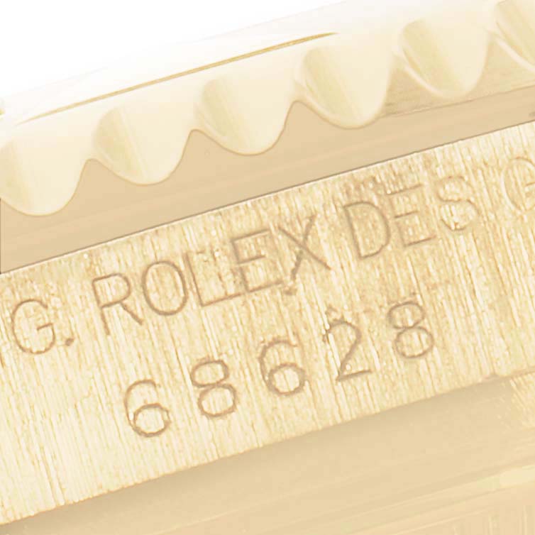 This image shows a close-up of the case side of a Rolex Yacht-Master 68628 Men's Yellow Gold White Dial 68628 Men's Yellow Gold White Dial watch, focusing on engraved details and part of the bezel.