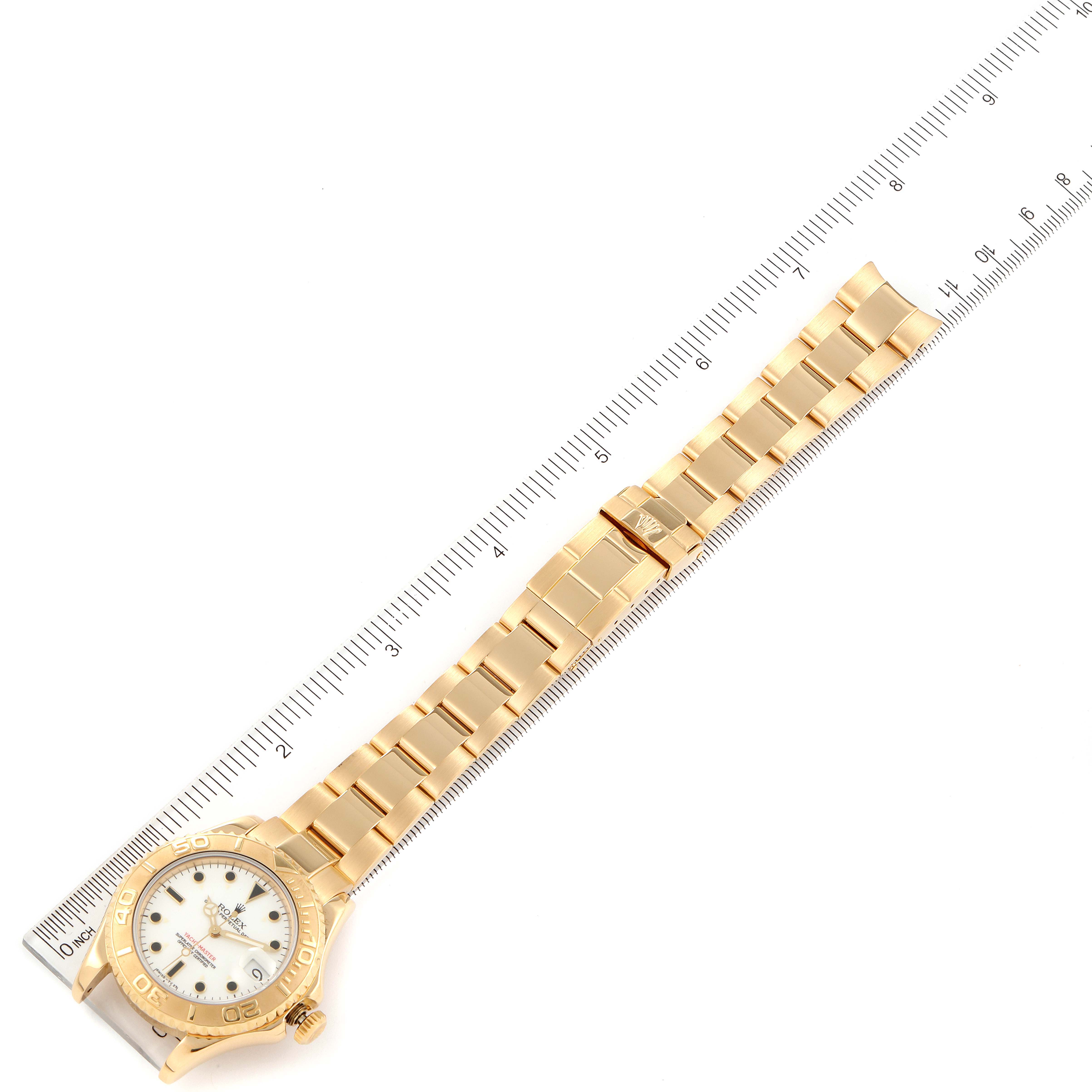 The Rolex Yacht-Master 68628 Men's Yellow Gold White Dial 68628 Men's Yellow Gold White Dial watch is displayed in a top-down view, showing its face, bezel, and bracelet, with a ruler for scale.