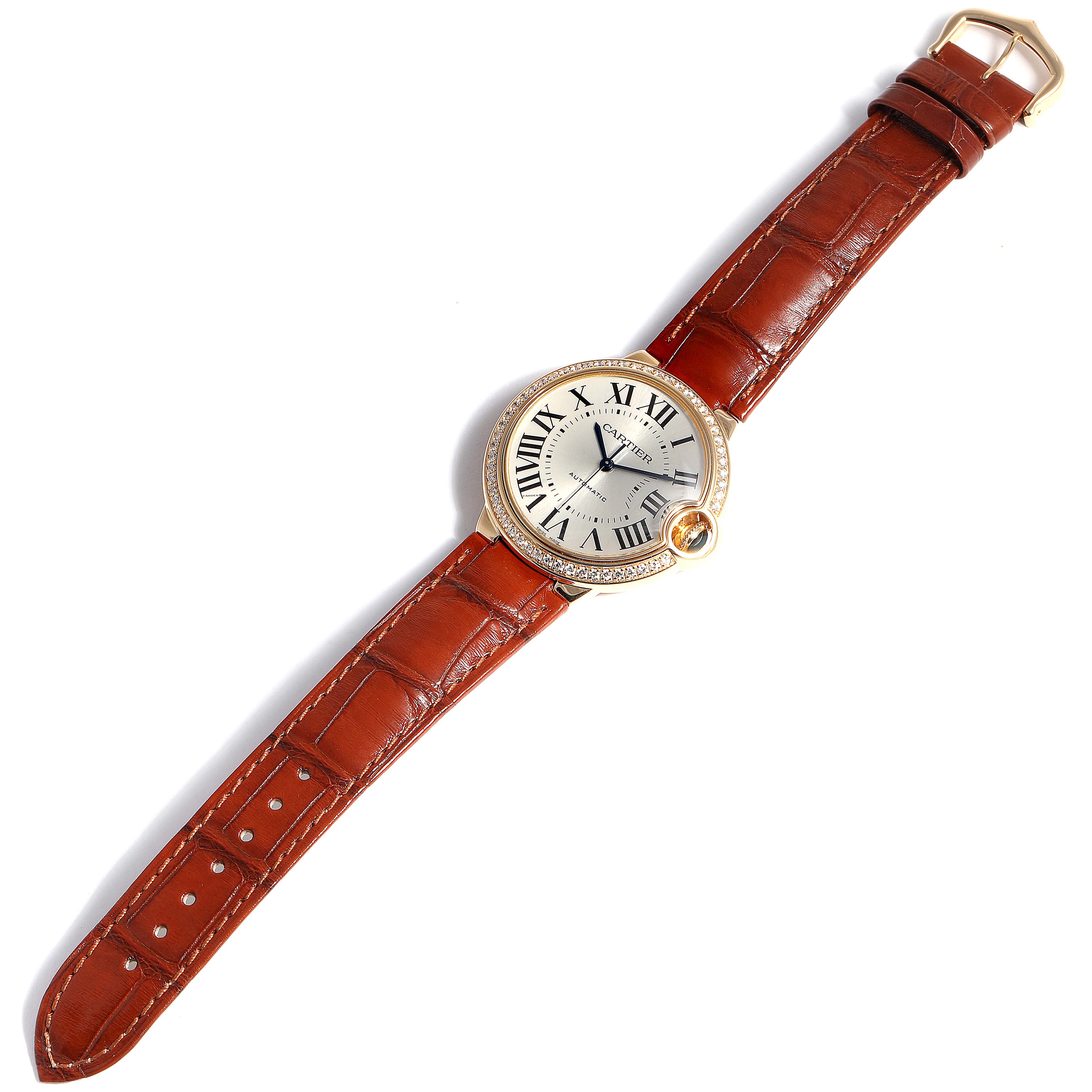 The image shows a Cartier Ballon Bleu WE900451 Women's Yellow Gold Silver Dial WE900451 Women's Yellow Gold Silver Dial watch from a top-down angle, highlighting its face, bezel, crown, and brown leather strap.