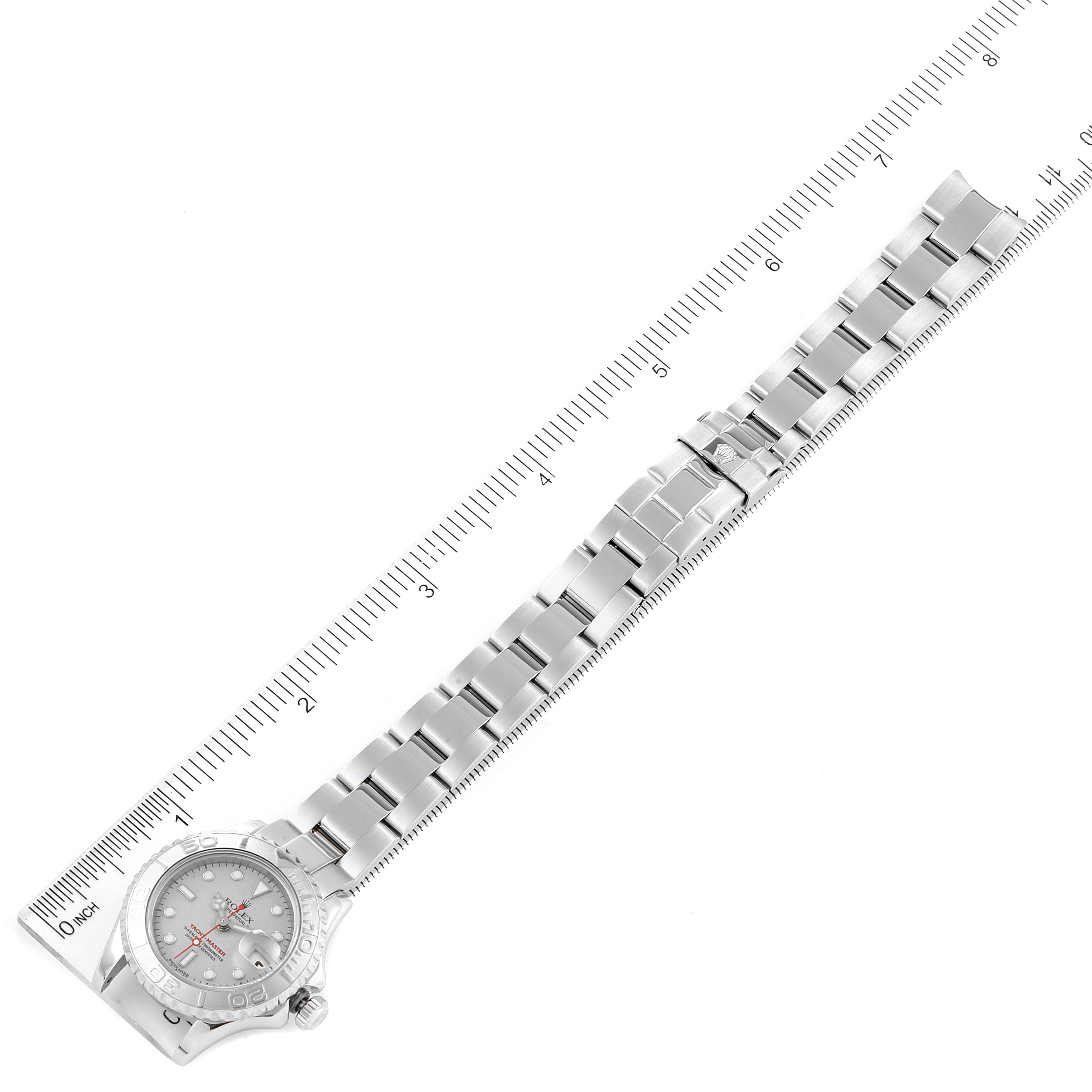 The Rolex Yacht-Master 169622 Women's Stainless Steel Silver Dial 169622 Women's Stainless Steel Silver Dial watch is shown from a top-down angle, displaying its face and full metal bracelet alongside a ruler.