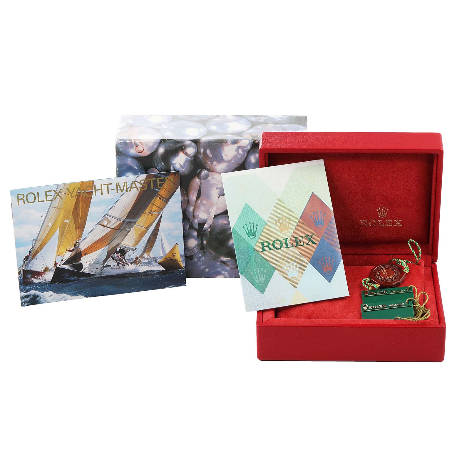 This image shows a Rolex Yacht-Master 169622 Women's Stainless Steel Silver Dial 169622 Women's Stainless Steel Silver Dial packaging with a red box, brochure, and accessories like a green tag and coin.