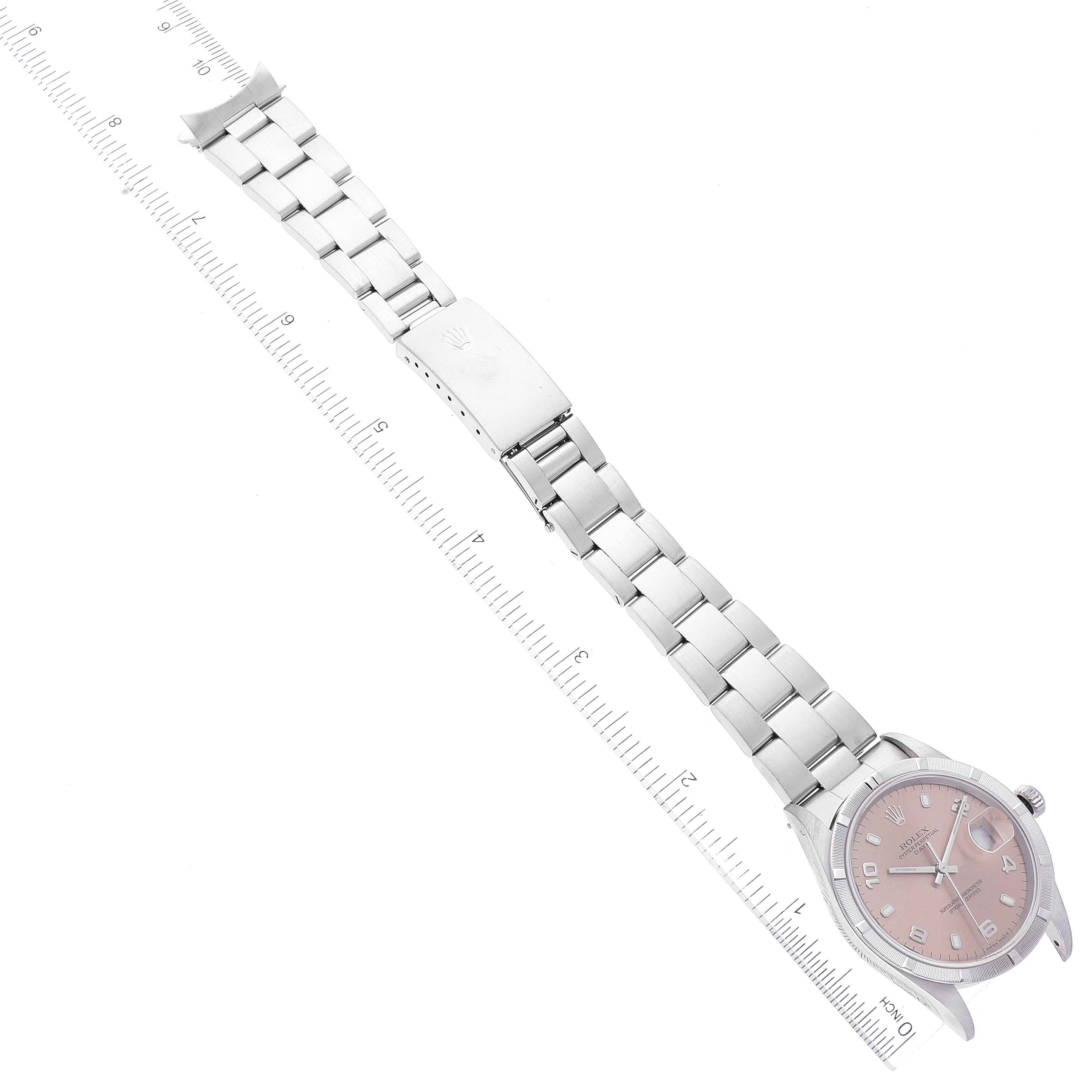 The image shows a Rolex Date 15210 Men's Stainless Steel Pink Dial 15210 Men's Stainless Steel Pink Dial model watch from an overhead angle, displaying the face, bracelet, and clasp next to a measurement scale.