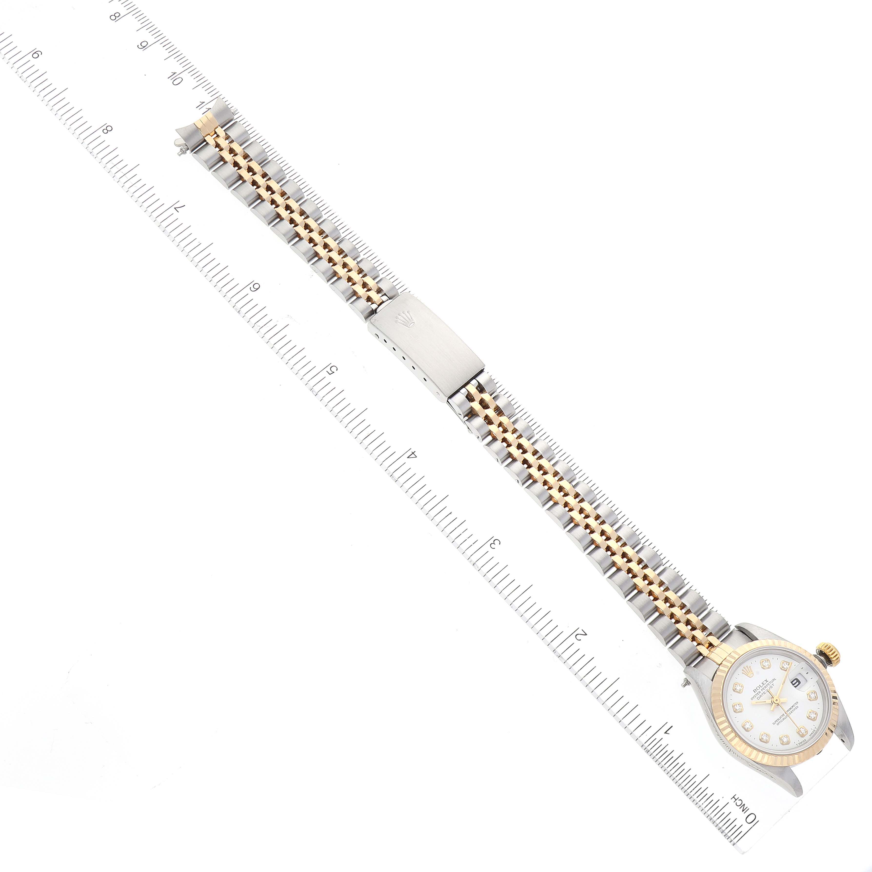 This image shows a Rolex Datejust 69173 Women's Steel and Gold (two tone) White Dial 69173 Women's Steel and Gold (two tone) White Dial watch from a top-down angle, displaying its face, bracelet, and clasp along a ruler for scale.