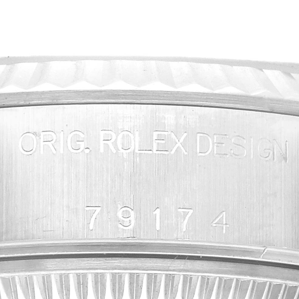 This image shows a close-up of the side of a Rolex Datejust 79174 Women's Stainless Steel Blue Dial 79174 Women's Stainless Steel Blue Dial watch, highlighting the engraving "ORIG. ROLEX DESIGN" and a serial number.