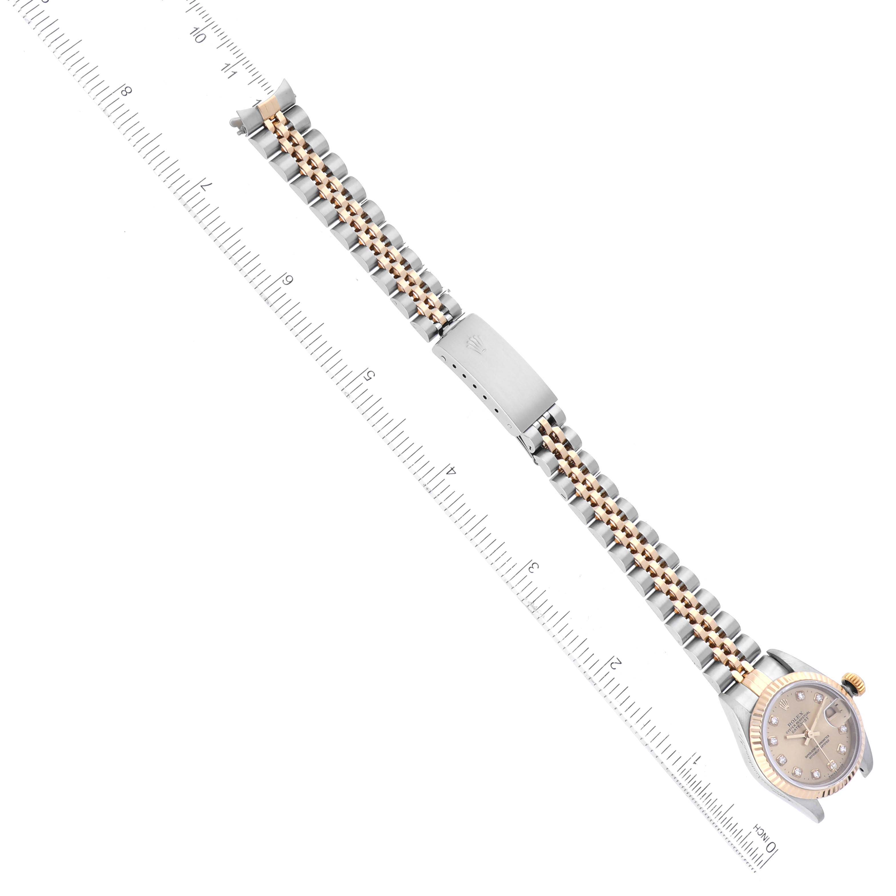 The image shows a top-down view of a Rolex Datejust 69173 Women's Steel and Gold (two tone) Champagne Dial 69173 Women's Steel and Gold (two tone) Champagne Dial watch, highlighting the face and metal bracelet alongside a ruler for scale.