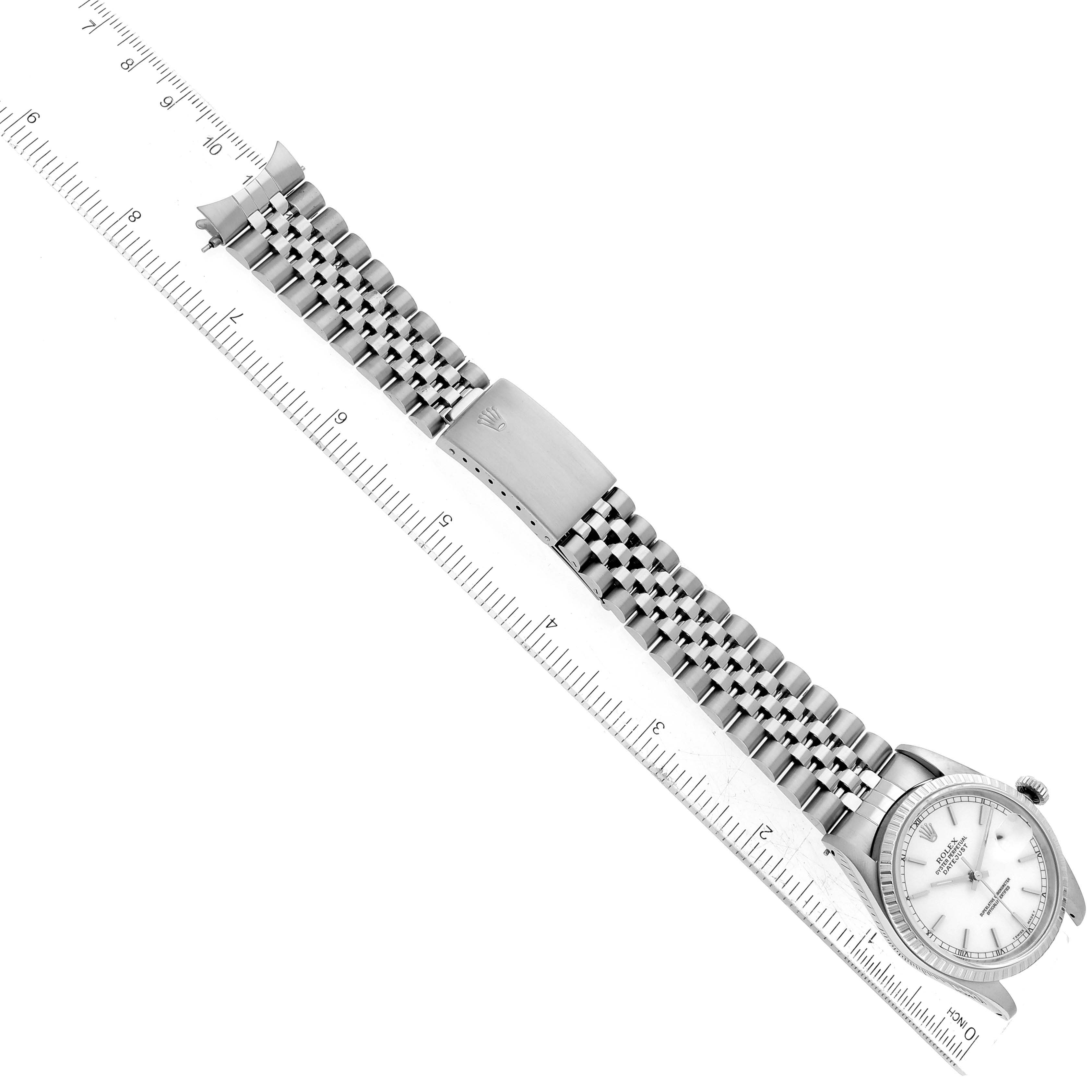 The image shows a top view of a Rolex Datejust 16220 Men's Stainless Steel White Dial 16220 Men's Stainless Steel White Dial watch with its bracelet and clasp extended alongside a ruler for scale.