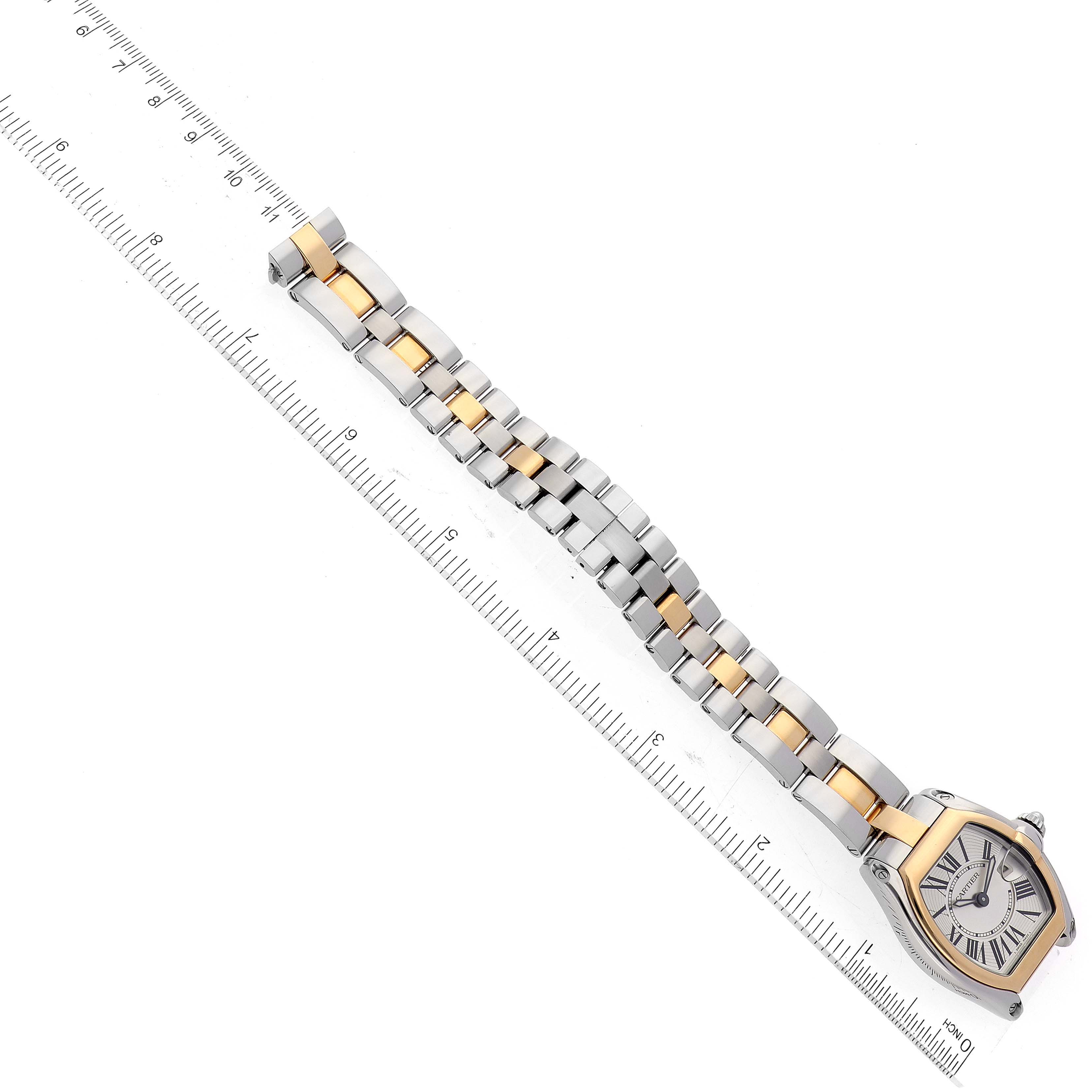 The image shows an overhead view of a Cartier Roadster W62026Y4 Women's Steel and Gold (two tone) Silver Dial W62026Y4 Women's Steel and Gold (two tone) Silver Dial watch with its stainless steel and gold bracelet extended next to a ruler.