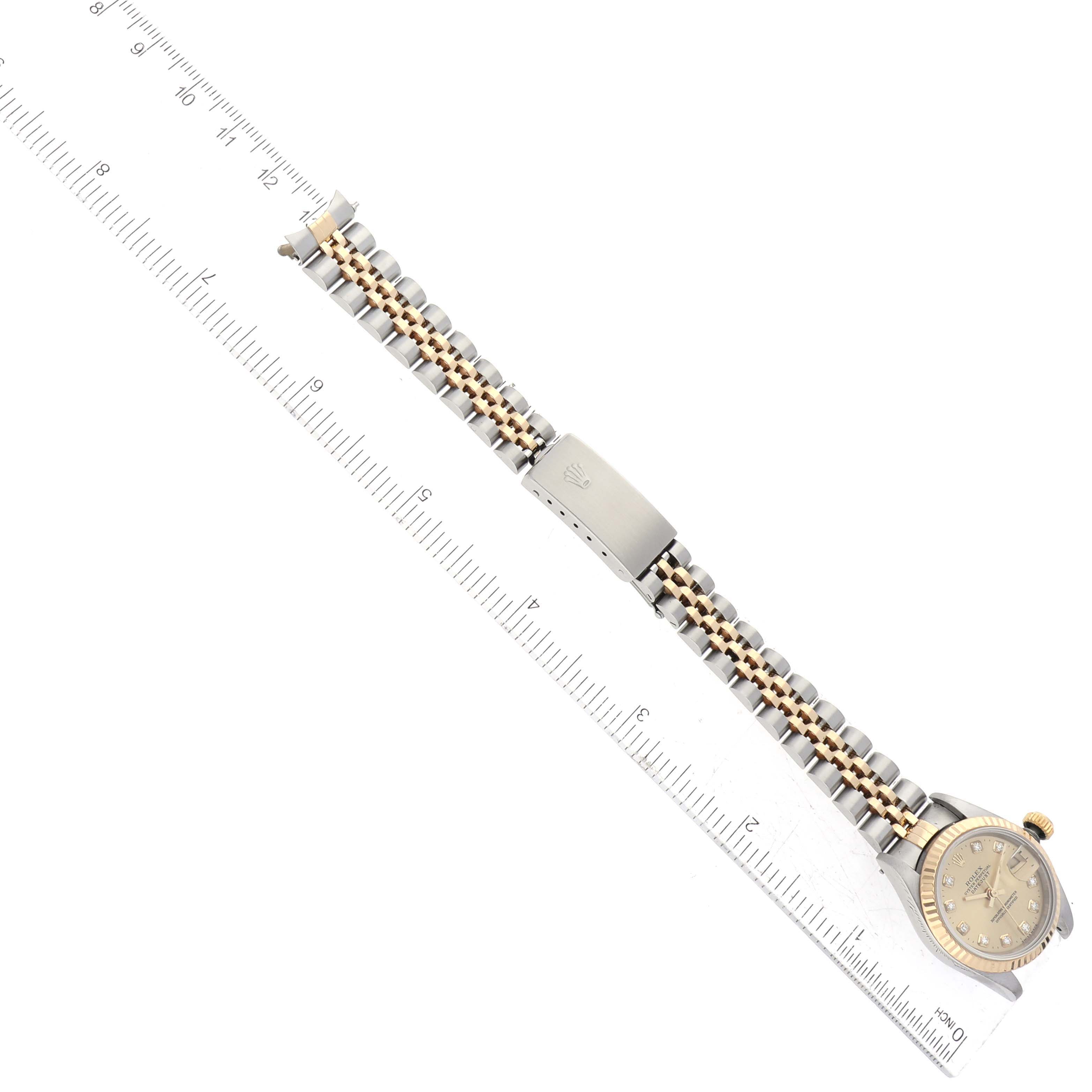 The Rolex Datejust 69173 Women's Steel and Gold (two tone) Champagne Dial 69173 Women's Steel and Gold (two tone) Champagne Dial watch is shown from a top-down angle, highlighting the bracelet, clasp, and part of the dial, alongside a ruler for scale.