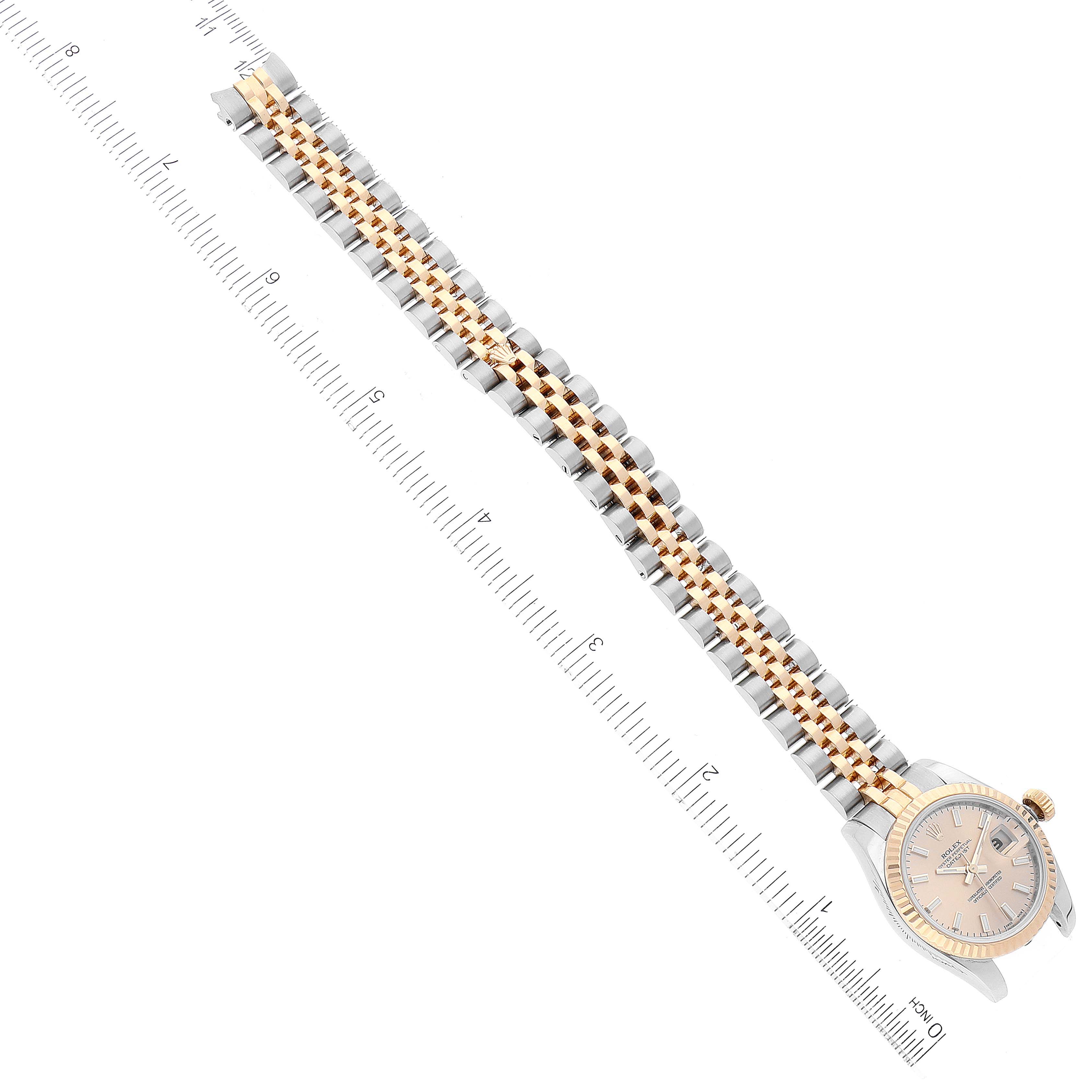 The image shows a top view of a Rolex Datejust 179173 Women's Steel and Gold (two tone) Champagne Dial 179173 Women's Steel and Gold (two tone) Champagne Dial watch, highlighting its face and two-tone bracelet next to a measuring ruler.