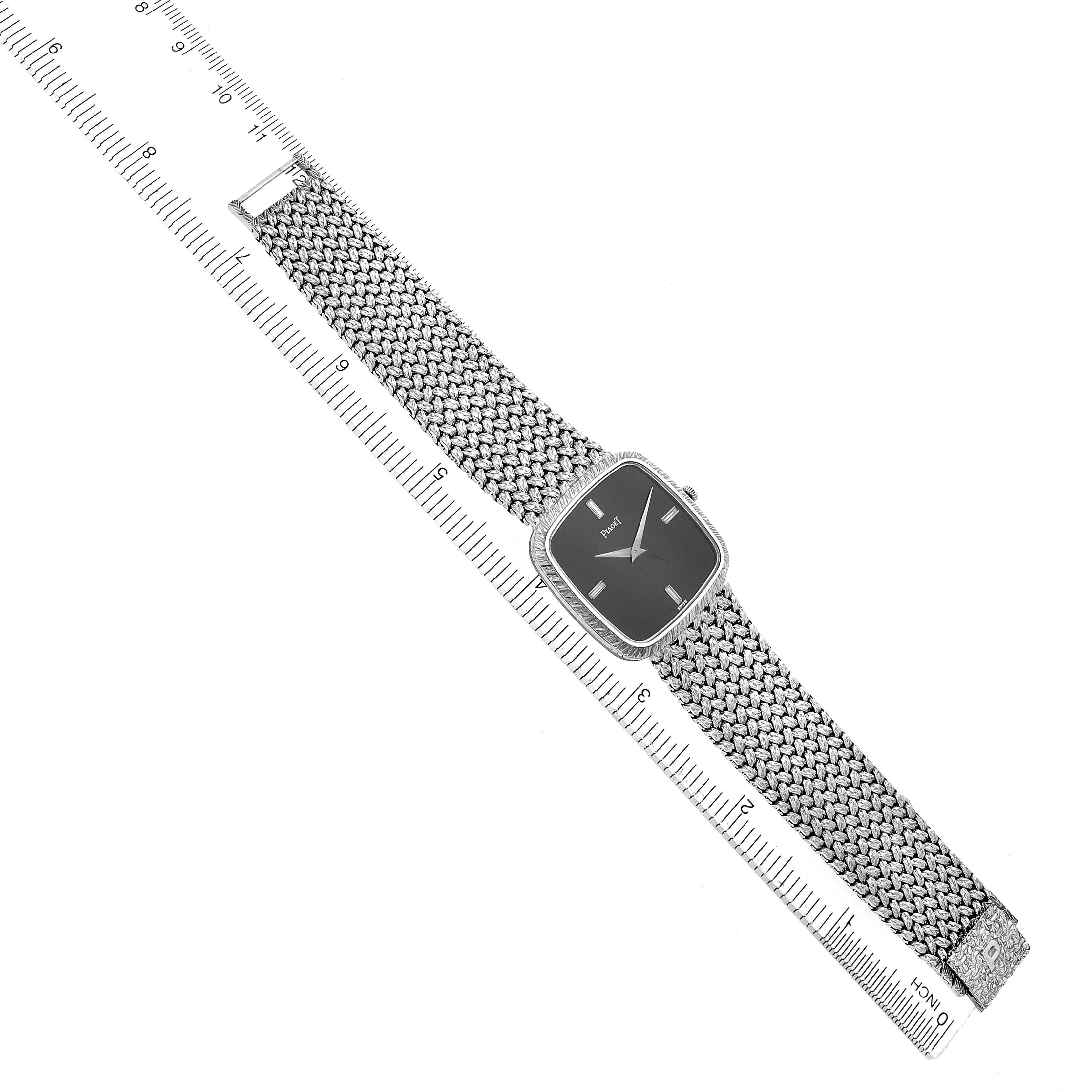 The Piaget 9771D2 men's watch is displayed from a top-down angle, showing its full face and woven bracelet, with a ruler for size reference.