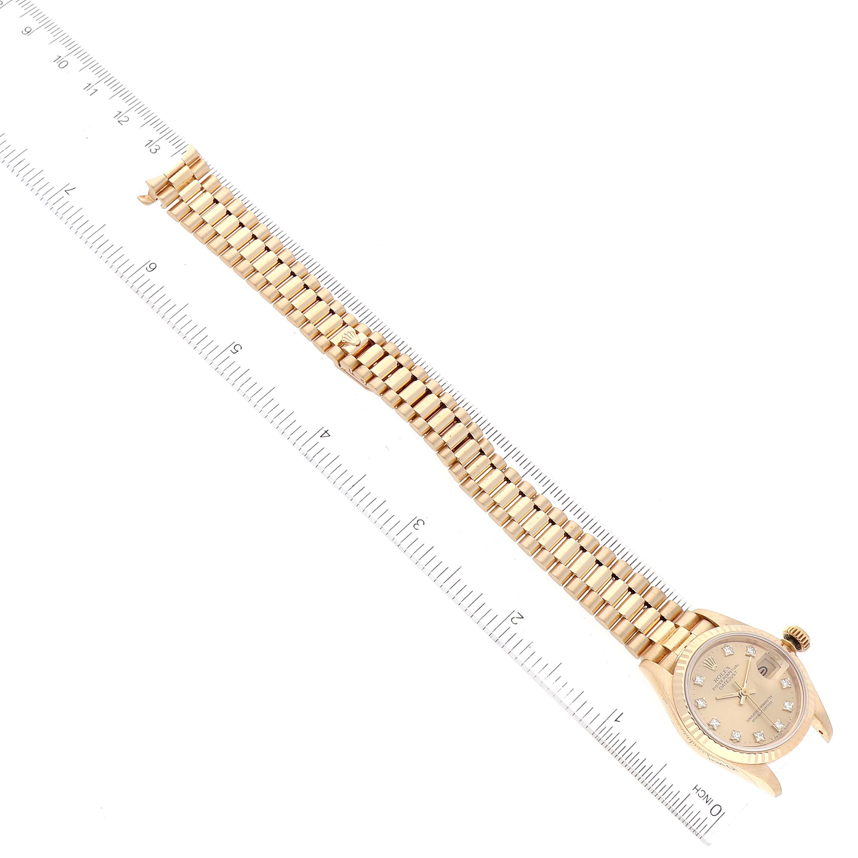 The image shows a Rolex President 69178 Women's Yellow Gold Champagne Dial 69178 Women's Yellow Gold Champagne Dial model watch viewed from above, including its case, crown, dial, and bracelet alongside a ruler.