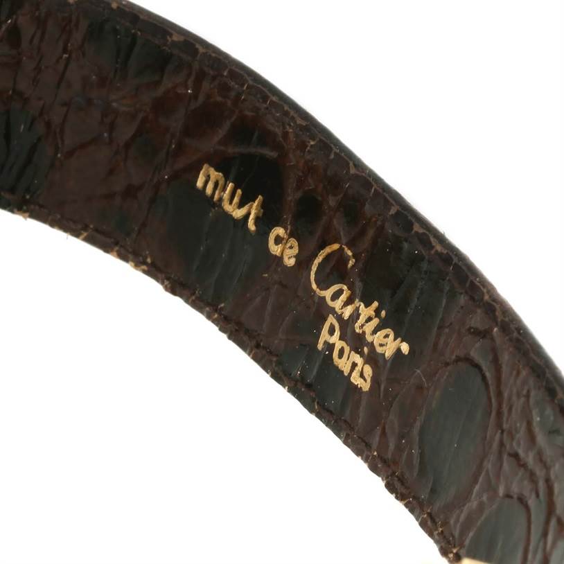 The image shows a close-up view of the Cartier Tank Classic Men's Yellow Gold White Dial Men's Yellow Gold White Dial watch's leather strap with "must de Cartier Paris" inscribed.