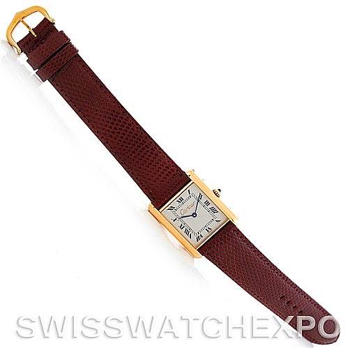 The image shows the Cartier Tank Classic Men's Yellow Gold Silver Dial Men's Yellow Gold Silver Dial model watch from a top-down angle, displaying its face, strap, and buckle.