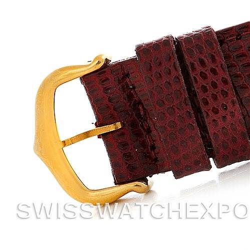 This image shows a close-up of the buckle and strap of a Cartier Tank Classic Men's Yellow Gold Silver Dial Men's Yellow Gold Silver Dial watch with a gold-toned buckle and red leather strap.