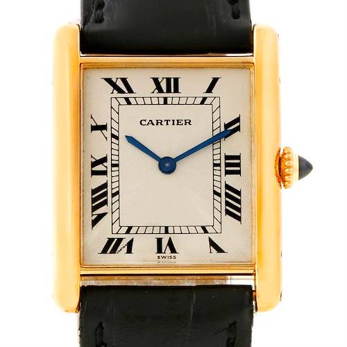 The image shows a front view of a Cartier Tank Classic Men's Yellow Gold Beige Dial Men's Yellow Gold Beige Dial watch with a gold case, blue hands, Roman numerals, and a black leather strap.