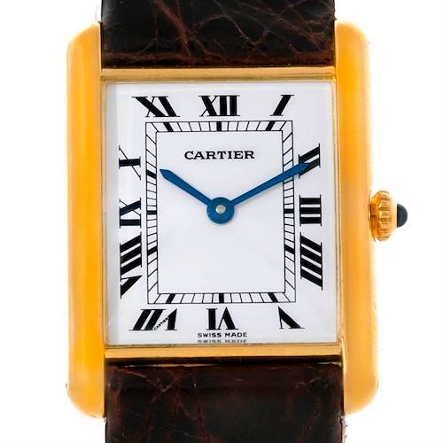The image shows a close-up of the Cartier Tank Classic 8810527329 Yellow Gold White Dial 8810527329 Yellow Gold White Dial watch face, emphasizing its Roman numerals and rectangular gold case.