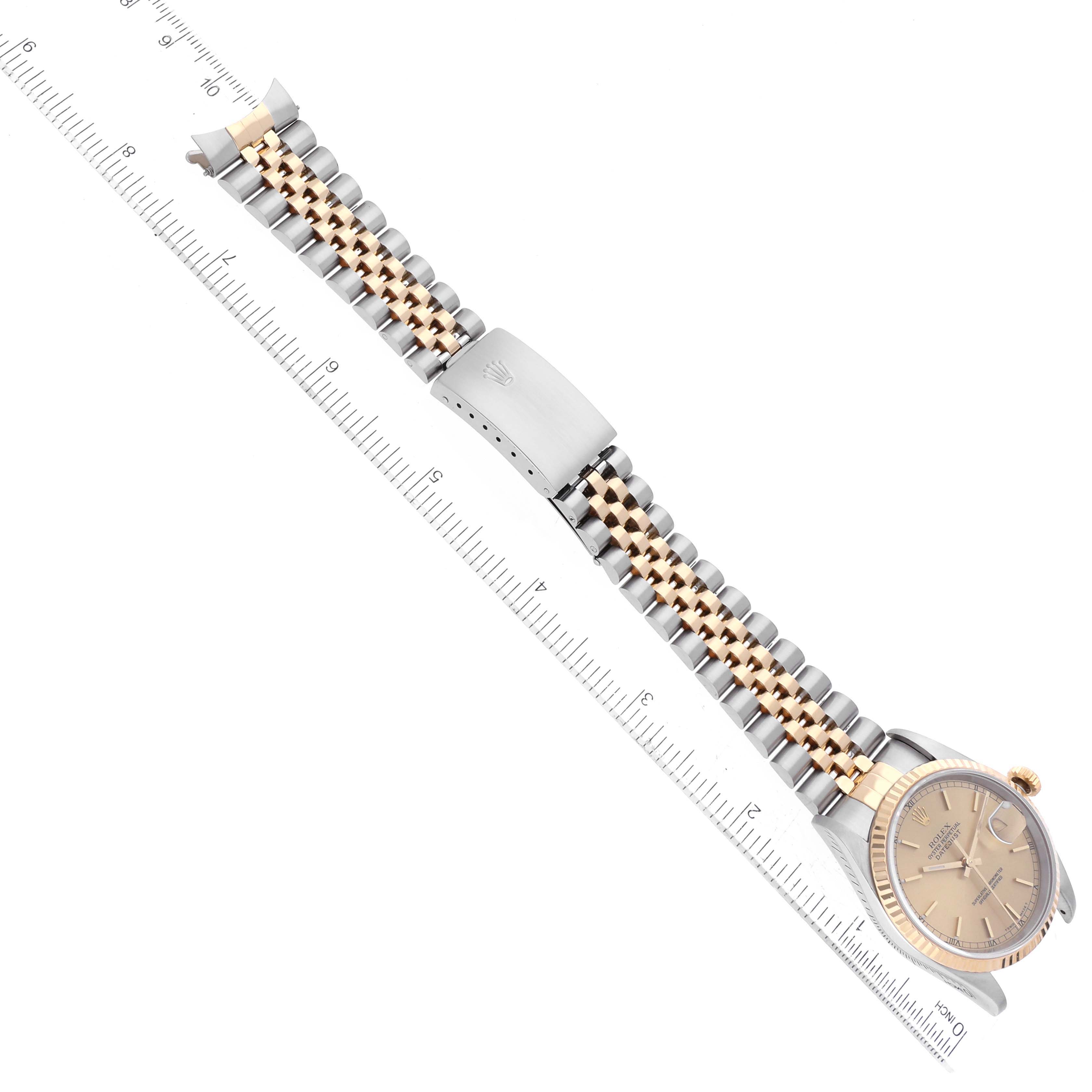 The Rolex Datejust 16233 Men's Steel and Gold (two tone) Champagne Dial 16233 Men's Steel and Gold (two tone) Champagne Dial watch is shown from a top-down angle, displaying the full bracelet, clasp, and watch face alongside a ruler.