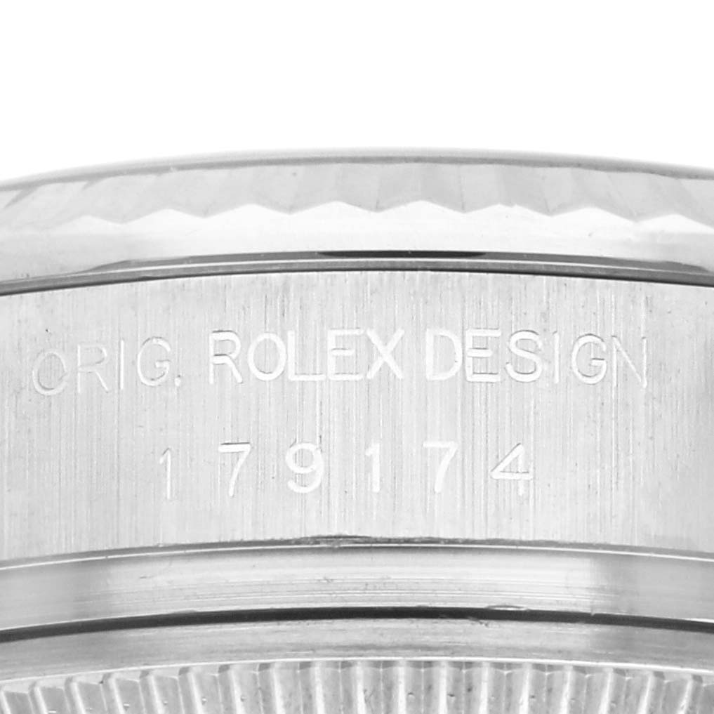 This image shows a close-up of the side of a Rolex Datejust 179174 Women's Stainless Steel Silver Dial 179174 Women's Stainless Steel Silver Dial watch, featuring the engraved serial number and "ORIG. ROLEX DESIGN" text.